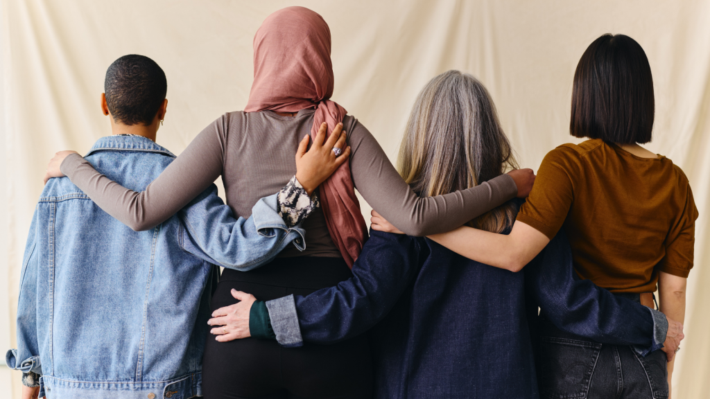 Rear view of four women with arms around each other in support of International Women's Rights Day