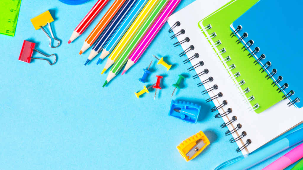 photo of colorful pencil, pens and notebooks on a blue background