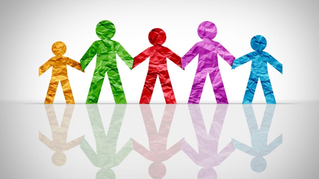 5 paper figures of different colours holding hands